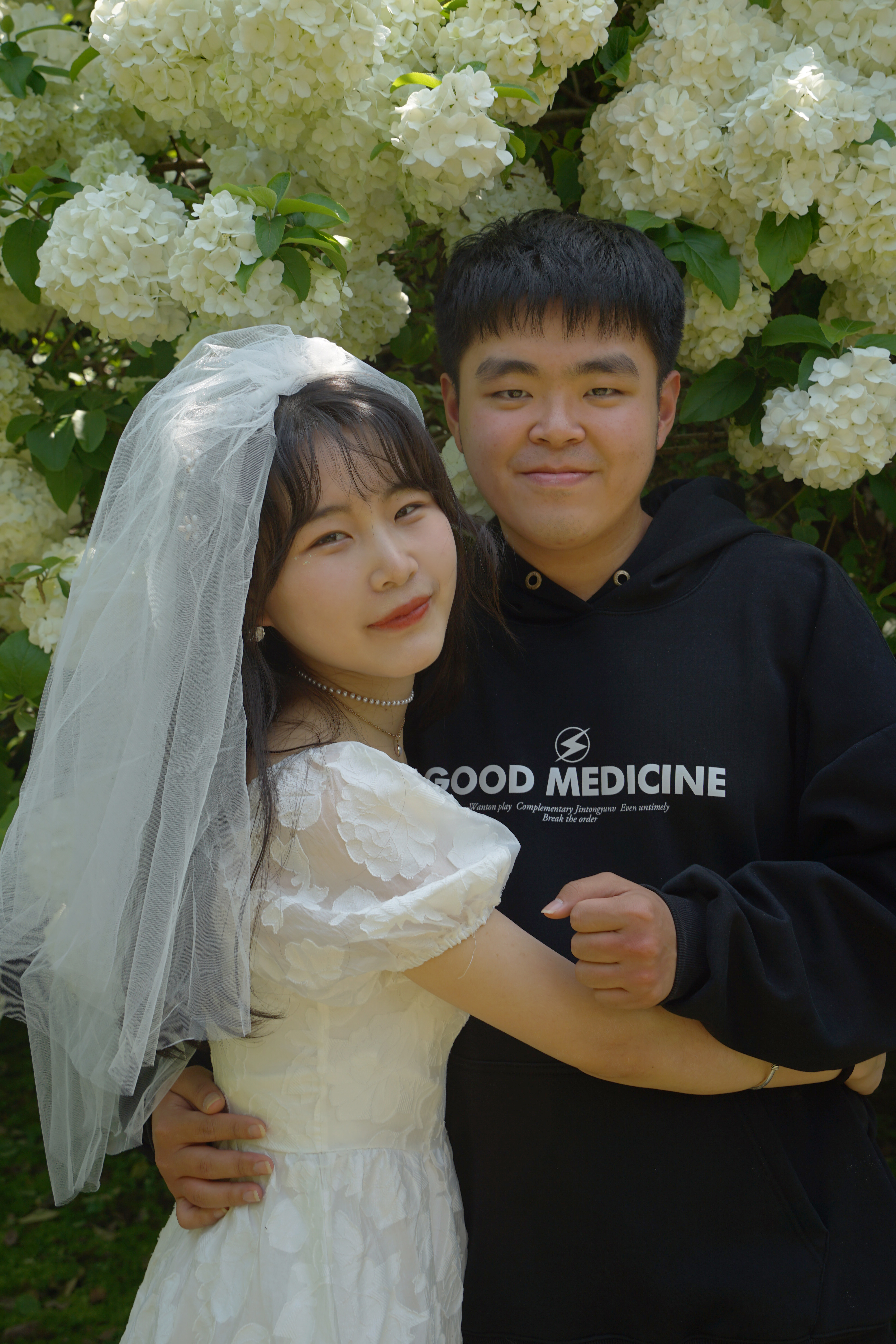My girlfriend and me standing together in front of white flowers
